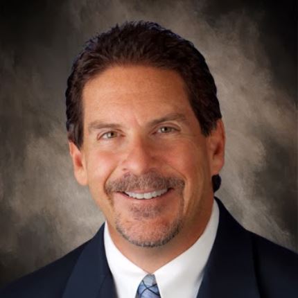 A man in suit and tie smiling for the camera.