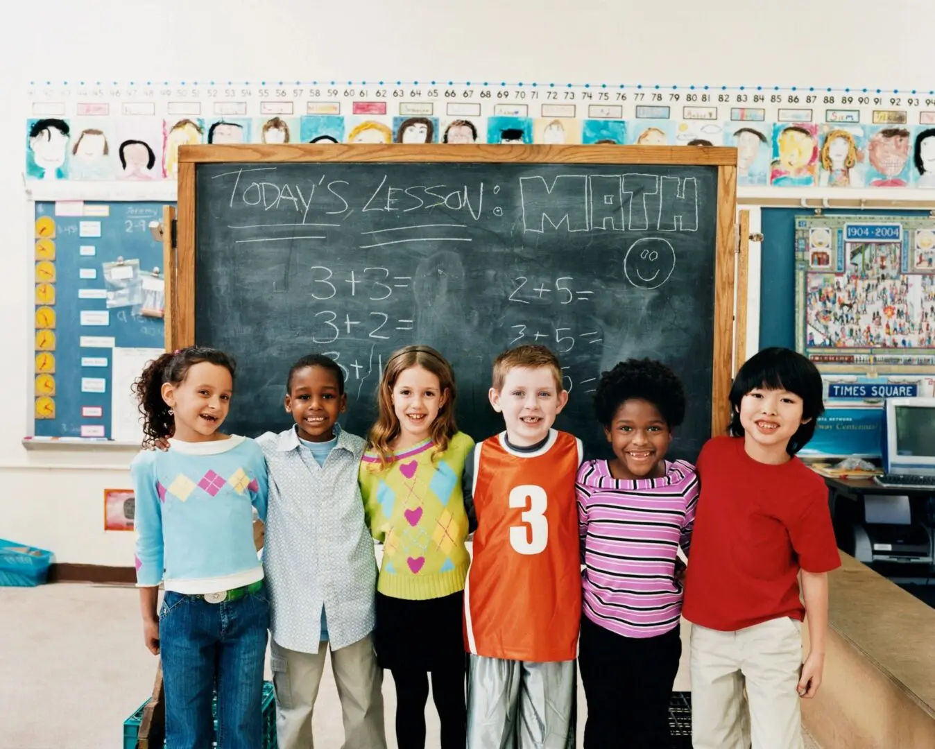 A group of children standing in front of a chalkboard.